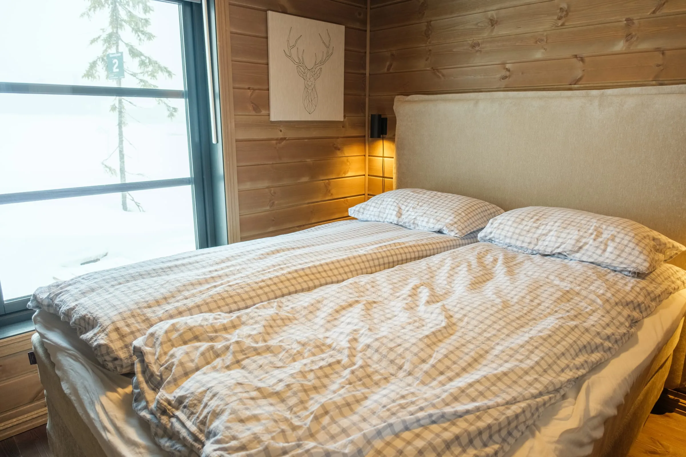 Bedroom dressed in checked bedding, looking out to the white slope