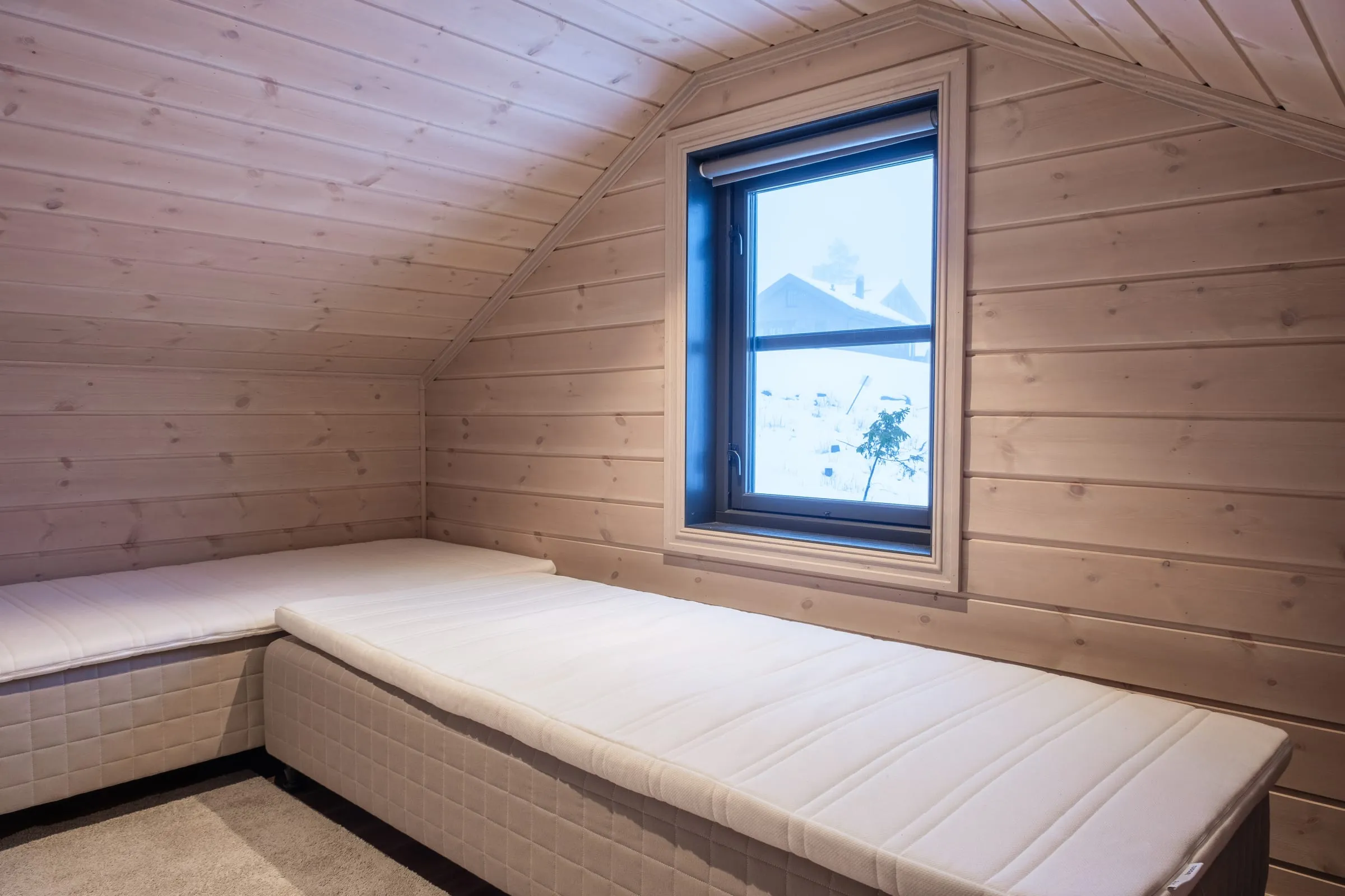 Loft room with twin beds tucked under the eaves and a snowy view