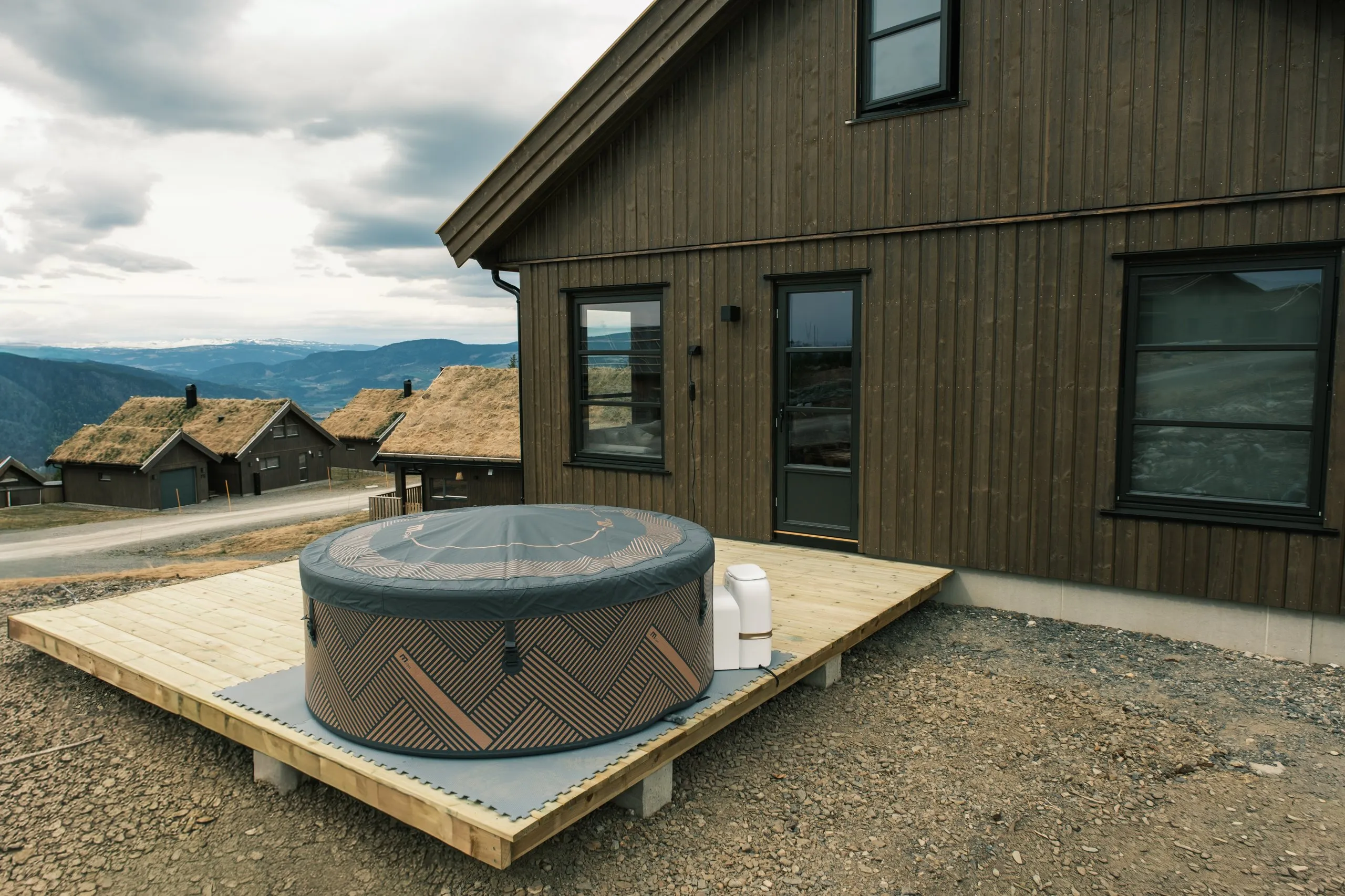 The cabin and its private hot tub on the deck, with the Hafjell valley beyond