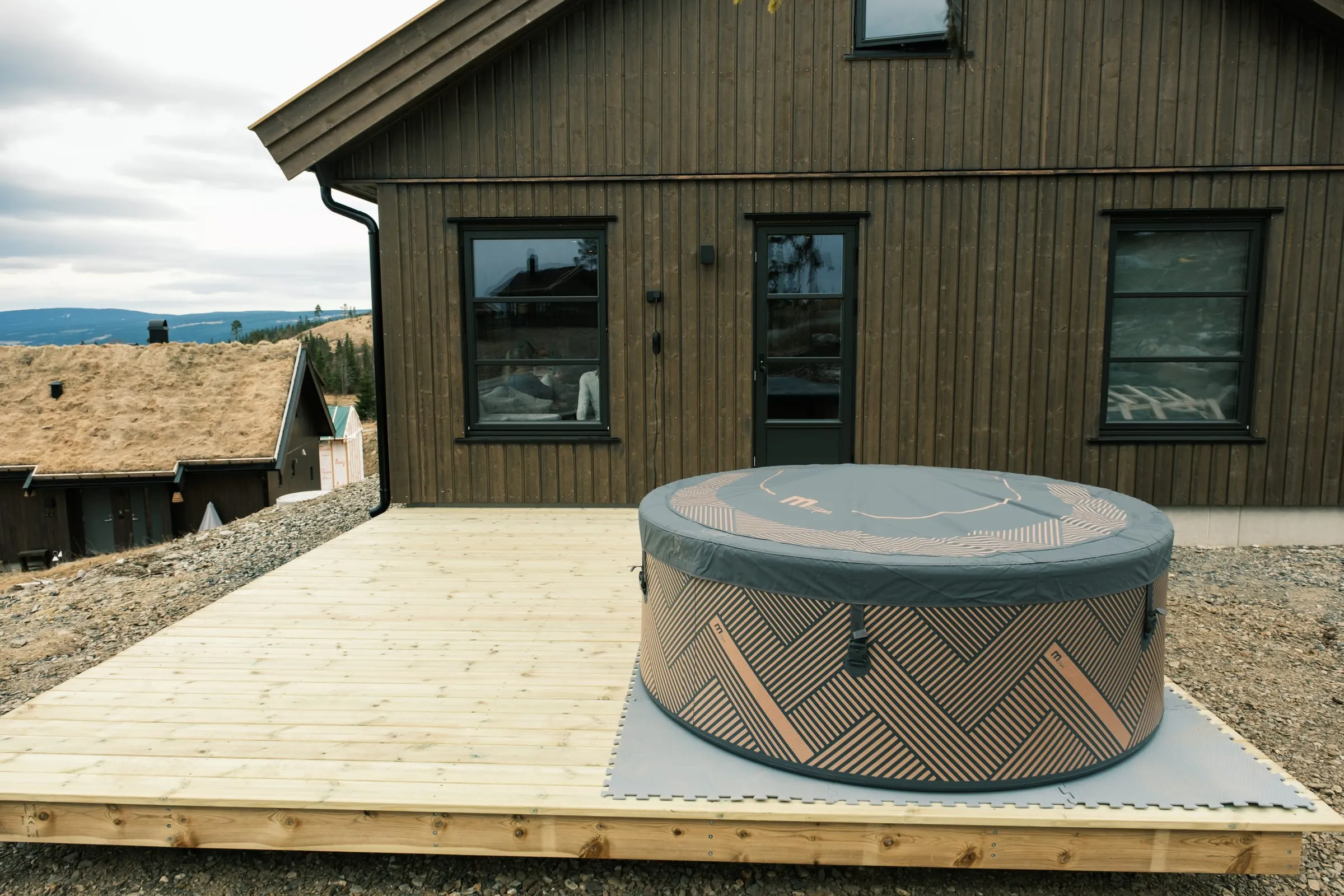 Private hot tub on the deck with the valley and turf-roofed cabins beyond