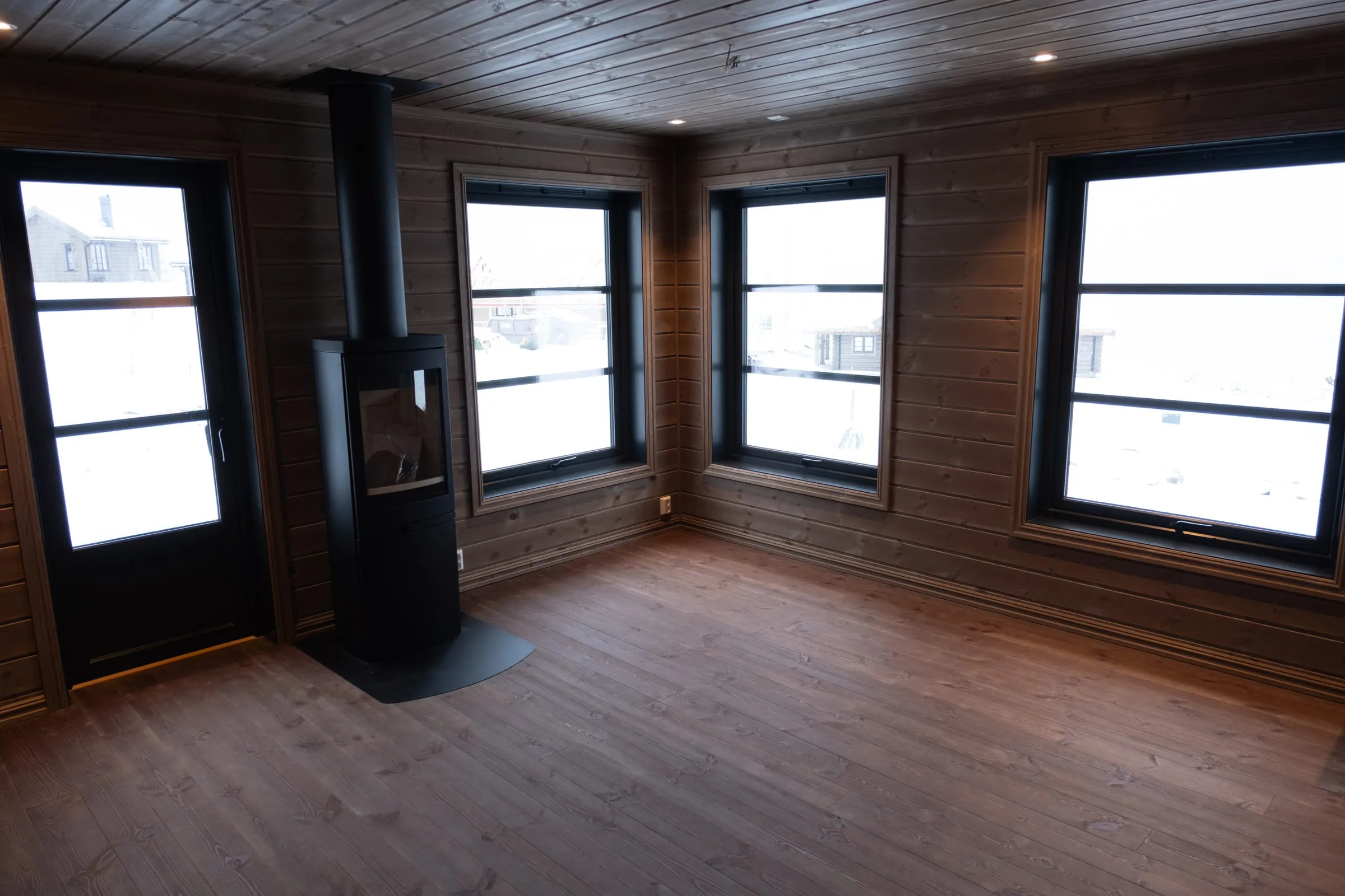 Living room flooded with daylight, wood stove and snow in every window