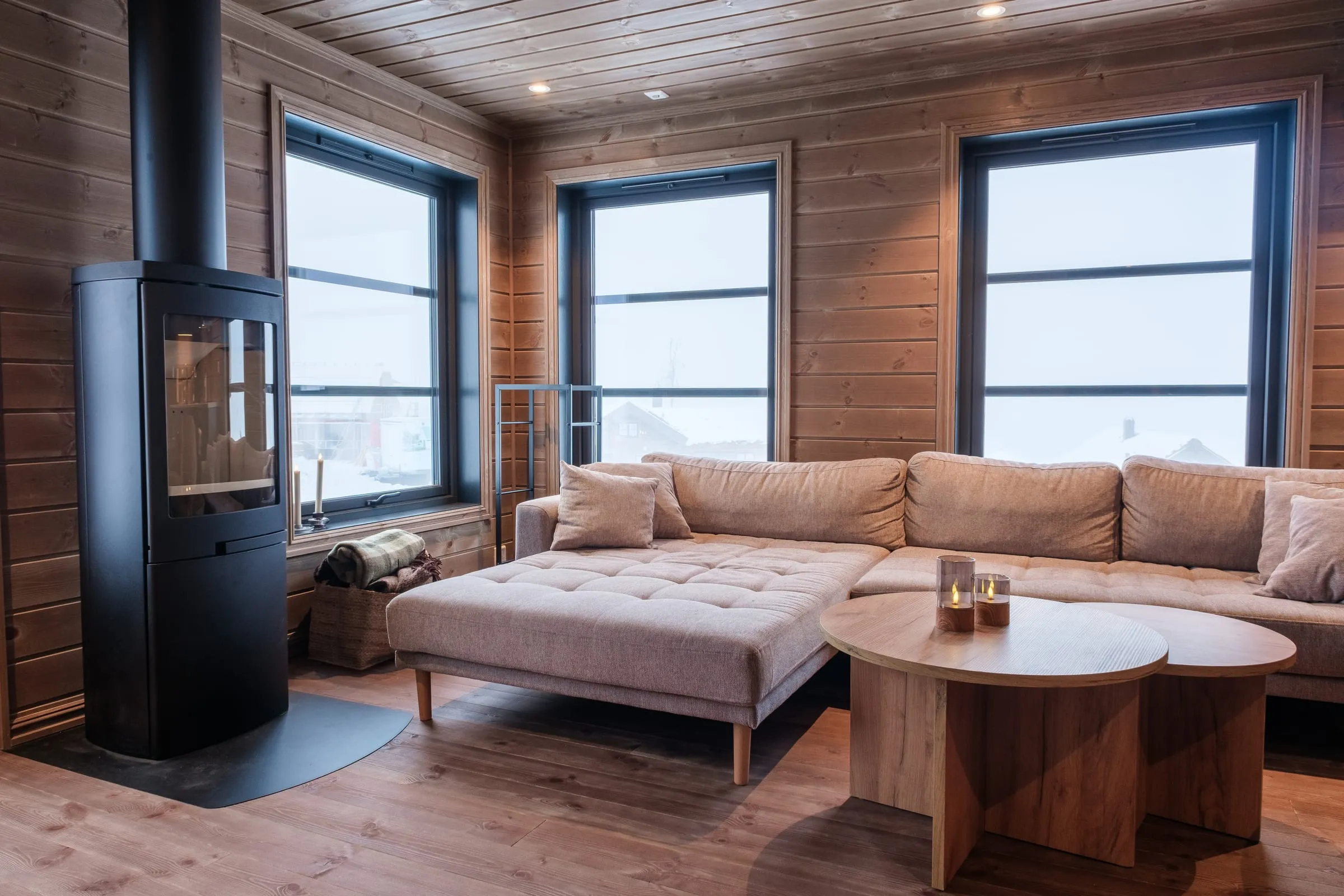 Cosy seating around the black wood stove, three tall windows onto the snow