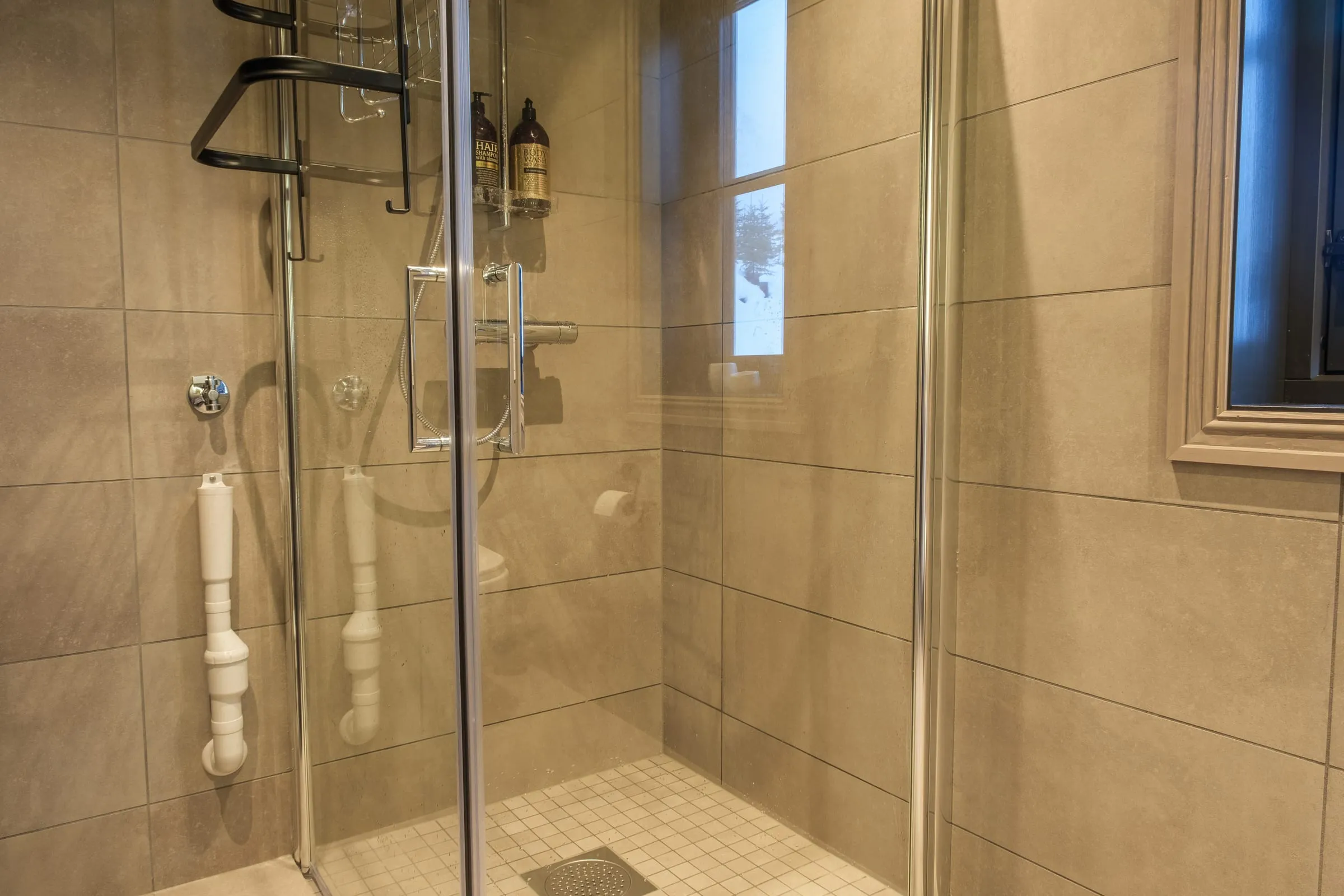 Walk-in glass shower in large-format stone tile